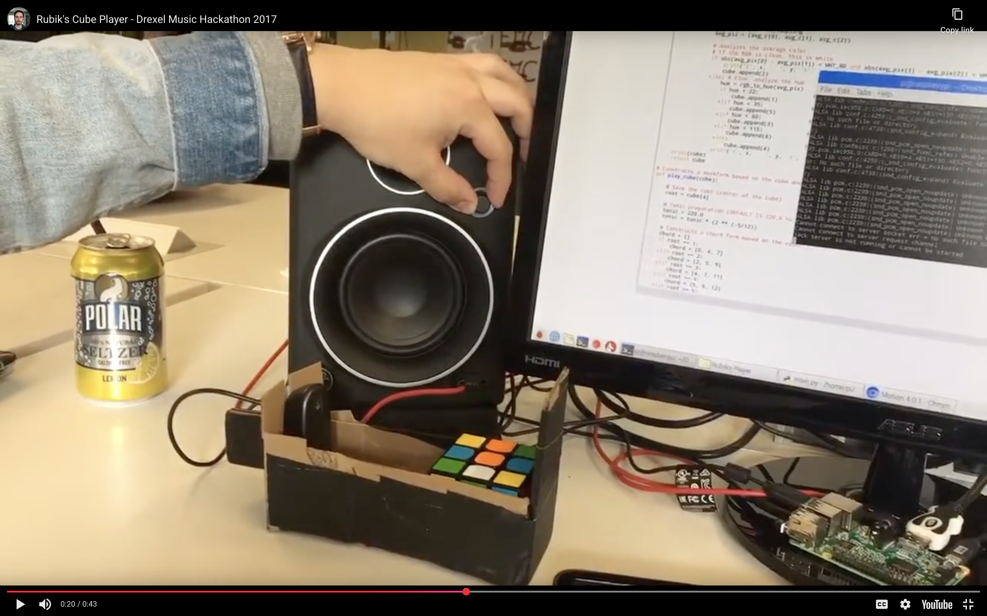 Rubik's Cube sonification hackathon project showing a Raspberry Pi setup with webcam reading cube colors and Python code on screen